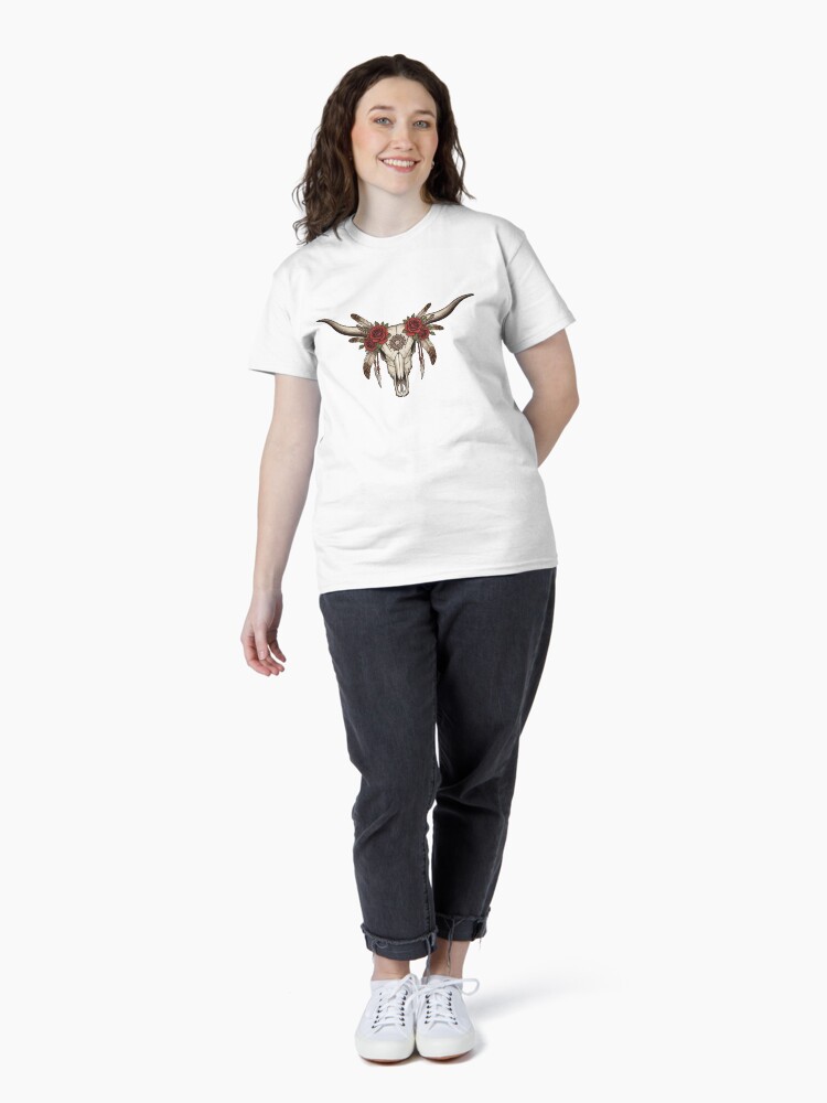 “Longhorn cow skull with feathers and roses in boho western style on rustic t-shirt – country girl aesthetic shirt design”