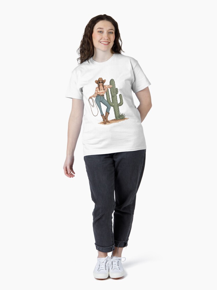 “Boho cowgirl t-shirt with cactus, hat, boots, and floral western design – feminine rodeo style”